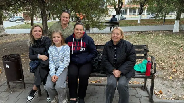 Чотири жінки і дівчинка на лавці в парку 