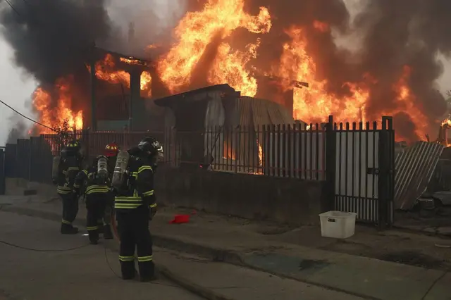 Bomberos frente a unas viviendas en llamas en la región del Biobío, Chile