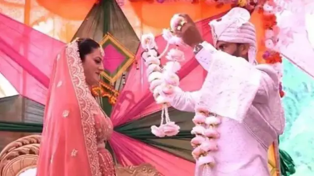 Sunita C y uno de sus maridos, Pradeep N, intercambian guirnaldas durante su ceremonia de matrimonio.