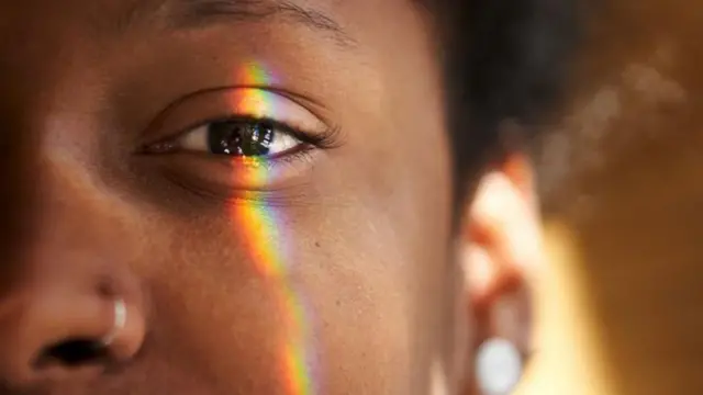 El lado izquierdo de la cara de una mujer con un rayo de luz sobre el ojo