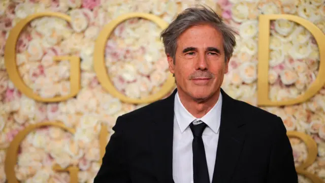 Walter Salles com sorriso tímido em frente a painel de evento