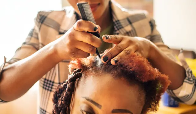 Mulher tendo seu cabelo trançado