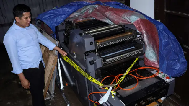 Personel polisi melihat kondisi mesin cetak yang merupakan alat bukti kasus pembuatan dan peredaran uang palsu di Mapolres Kabupaten Gowa, Sulawesi Selatan, Selasa (17/12/2024). Polres Gowa mengamankan alat bukti berupa satu unit mesin yang diduga digunakan untuk mencetak uang palsu di salah satu kampus universitas negeri di daerah itu yang melibatkan sedikitnya 15 orang tersangka. 
