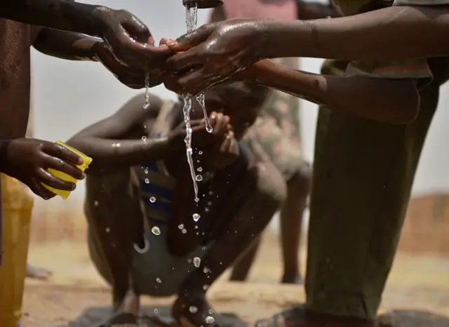 Des enfants se lavent les mains à la borne fontaine.