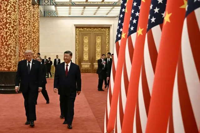Дональд Трамп и Си Цзиньпин идут по красному ковру вдоль установленных китайских и американских флагов в холле Дома народных собраний.