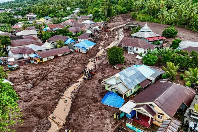 TOPSHOT - This aerial view shows rescue teams and residents searching for victims buried in mud after a flashflood hit the village of Rua located at the foot of Mount Gamalama, in Ternate, North Maluku on August 25, 2024. (Photo by AZZAM RISQULLAH / AFP) (Photo by AZZAM RISQULLAH/AFP via Getty Images)