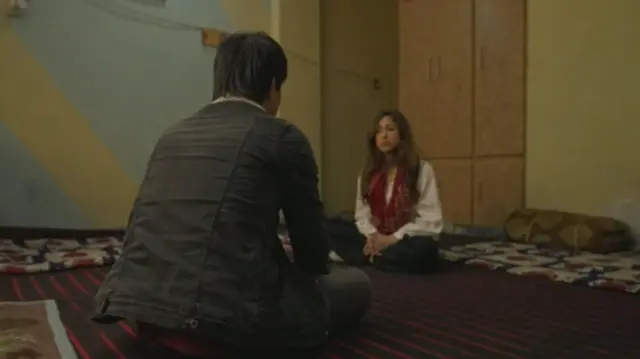 Azadeh Moshiri zaune a kasa. 