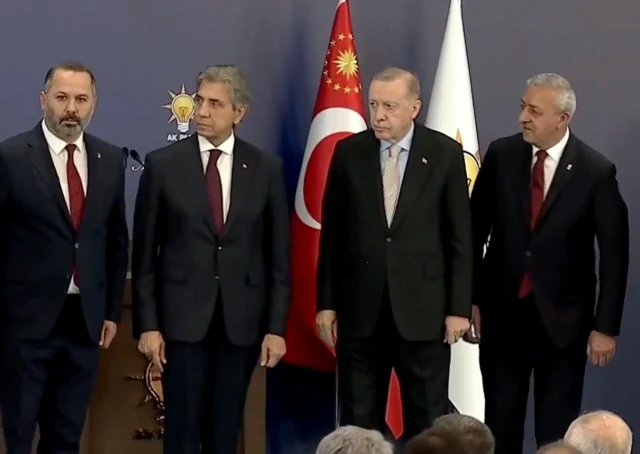 Cumhurbaşkanı Erdoğan yeni katılımları sahnede tanıtıyor, yanında üç takım elbiseli siyasetçi var