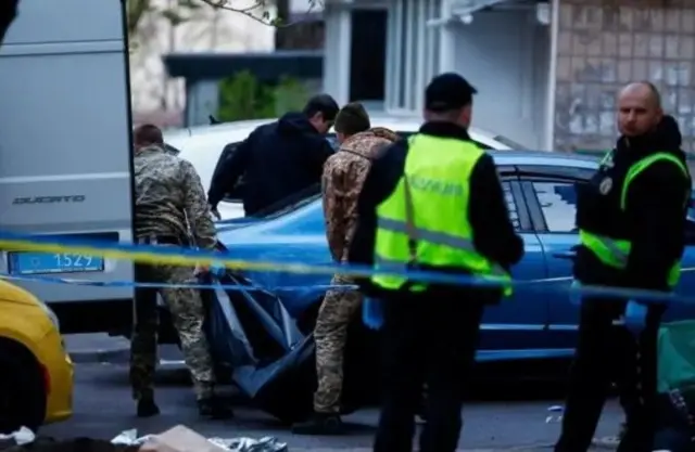 Чоловіки виносять тіло у пакеті 