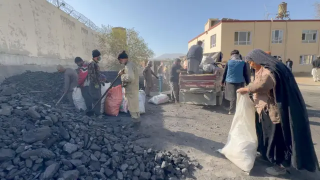 زنی در حال پرکردن بوجیپلاستیکی سفید با زغال در یکی از مراکز توزیع زغال سنگ دولتی در کابل نوامبر ۲۰۲۵
