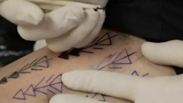 يد شخص ترسم وشوما