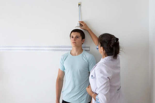 Une dame mesure la croissance d'un adolescant