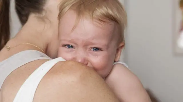 Bebê chorando no colo da mãe