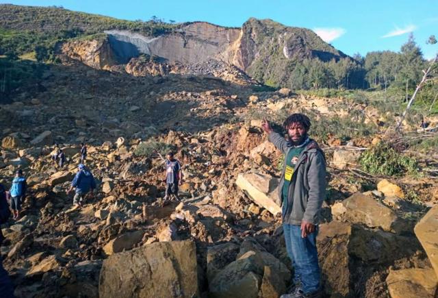 Un hombre señala la elevación geográfica que se derrumbó sobre la aldea en Papúa Nueva Guinea.