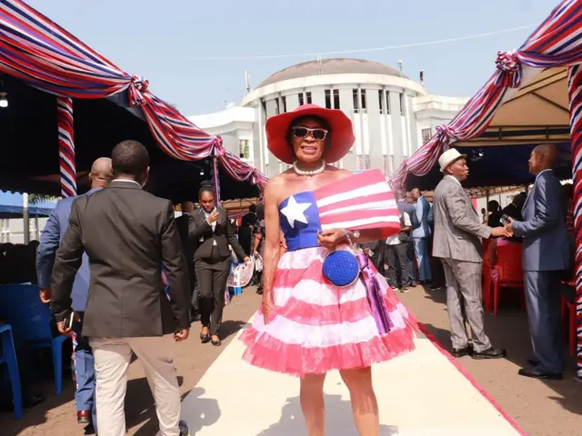 A woman stands outside the capitol building wearing a dress modelled after the Liberian flag.