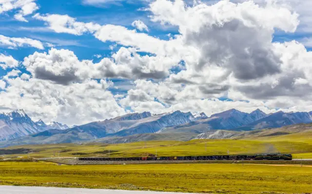 Trem passandoroleta do neymarárea verde, com montanhas nevadas ao fundo 