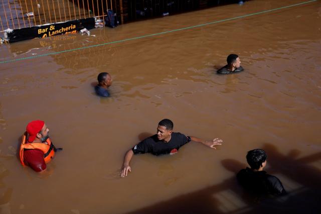 Homens andam por ruas inundadas em busca de sobreviventes em Canoas