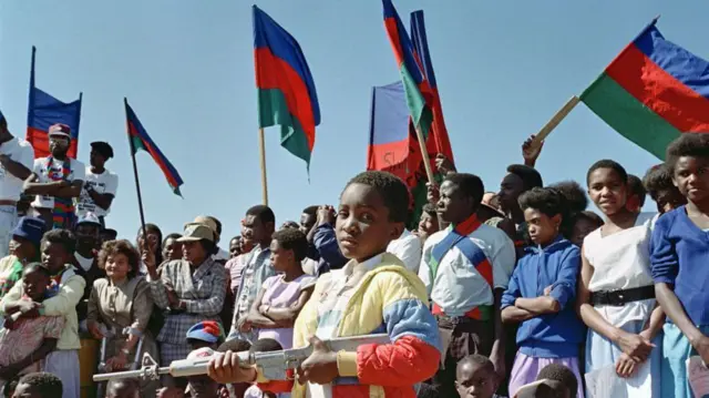 Ibihumbi n’ibihumbi vy’abashigikiye Swapo (South West Africa People's Organisation) bariko bararirimba indirimbo z’ubwigenge, mu gikorane co guhimbaza imyaka 22 y’intambara yabo kuri Afrika y’Epfo yari ikibandanya kwigarurira Namibia, ku wa 28 Myandagaro , 1988 I Windhoek.