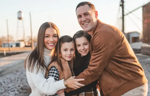 
سټیفني هنراهان (کیڼ اړخ ته) او د هغې میړه (ښي اړخ ته) خپلو دوو ماشومانو (منځ کې) سره چې منځ کې دي یو بل ته یې غېږ ورکړې.
