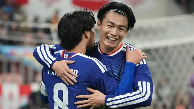 青いユニホーム姿の上田選手がチームメートと抱き合って笑顔を見せている