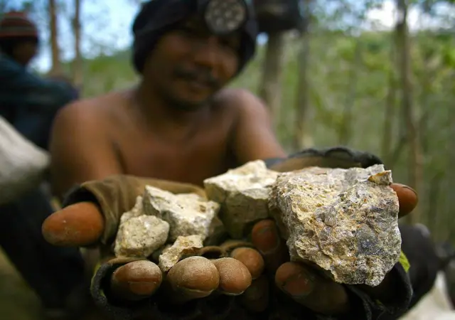 Ilustrasi. Foto menampilkan seorang penambang ilegal memamerkan batuan yang mengandung mineral emas. 