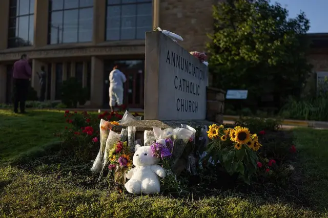 Белый мишка среди цветов возле знака с названием церкви