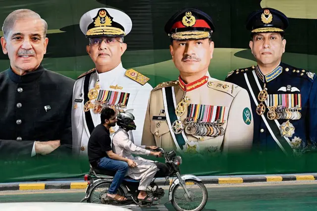 یک تصویر در خیابانی در یکی از شهرهای پاکستان را نشان می‌دهد که در آن سه مقام ارشد نظامی به شمول آصم منیر و نخست‌وزیر شهباز شریف دیده می‌شوند.