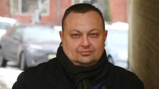 Алексей Антипович на улице в пальто и шарфе, с непокрытой головой