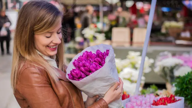 امرأة تمسك باقة من الورود