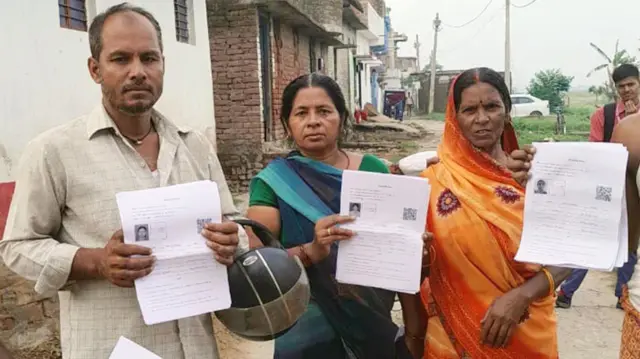 गणना फॉर्म के घर-घर वितरण के दौरान फॉर्म दिखाती महिलाएं