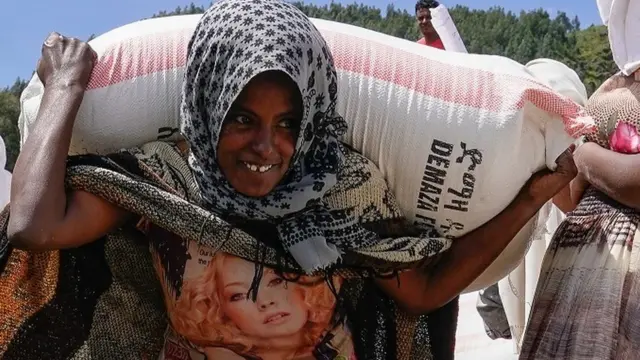 በአማራ ክልል በጭና አካባቢ የምትኖር ሴት ስንዴ ተሸክማ