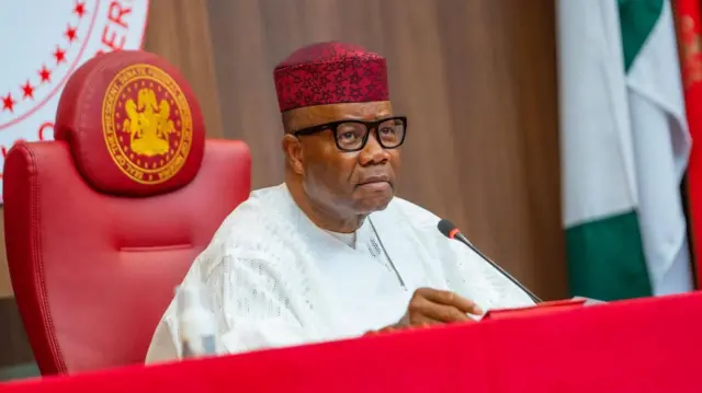 Nigeria Senate President Godswill Akpabio wear red cap and white dress. E siddon ontop red chair with microphone for im front