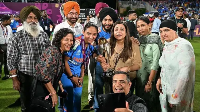 India's captain Harmanpreet Kaur (C) poses with family after winning the World Cup 