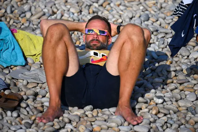Un hombre observa el eclipse desde una playa de Inglaterra.