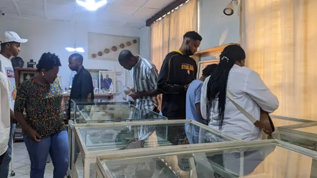 Des visiteurs à l'intérieur du musée regardant les pierres précieuses à travers les vitres