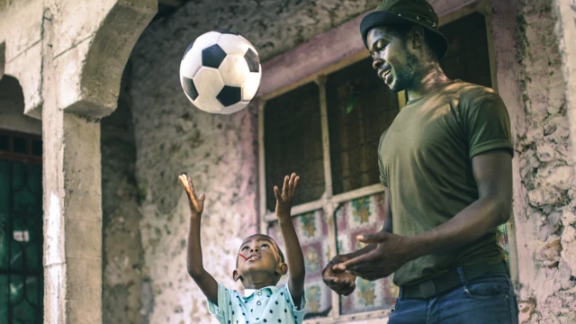 Boy throw ball for up wit im papa