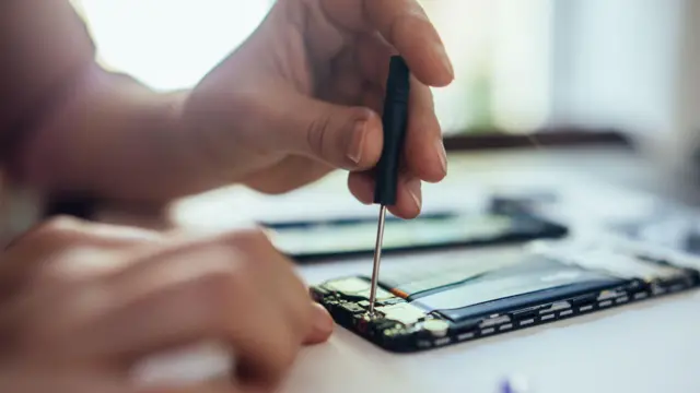 मोबाइल की मरम्मत करता एक व्यक्ति