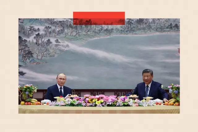 Putin reunido con Xi en Pekín; ambos están sentados frente a una mesa llena de frutas y flores.