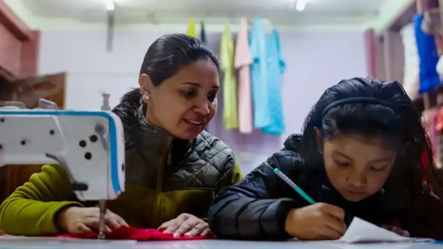 زنی در مقابل دختر خردسال نشسته است و با کودک در درس‌هایش کمک می‌کند