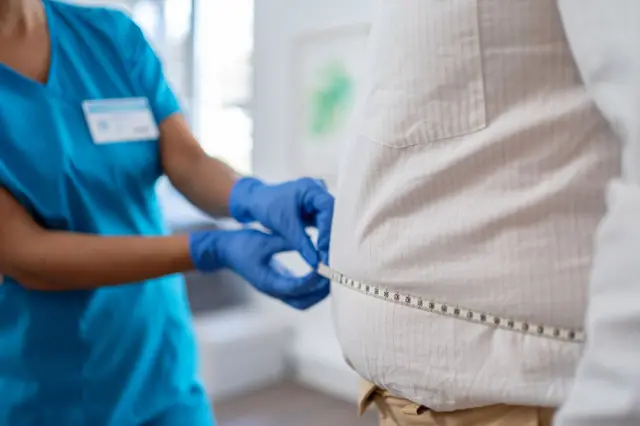 Médecin qui mesure le tour de taille d'un homme