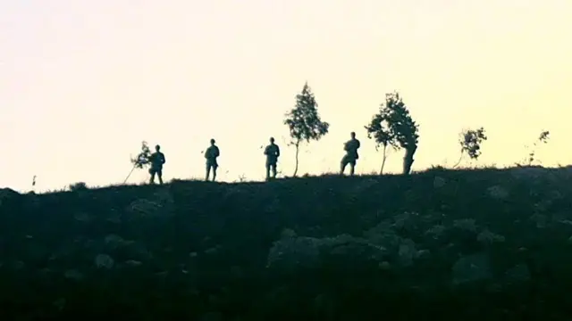 Bir tepenin üzerinde silahlı gibi görünen dört kişinin silüeti