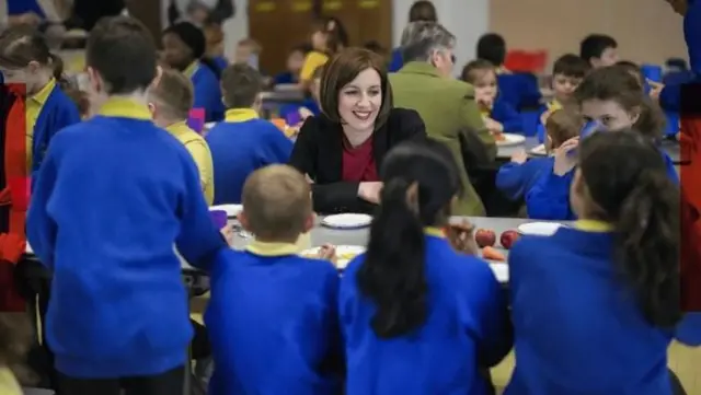 یک معلم در میان دانش‌آموزان نشسته و در حال صحبت با آنهاست