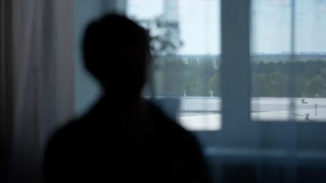 Марьяна — жена погибшего военнослужащего, ее темный силуэт на фоне окна