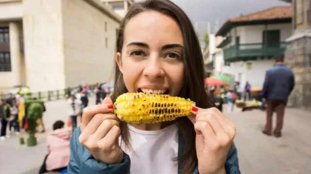 Mulher comendo um milho assado