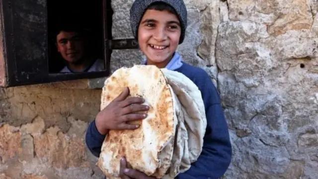 طفل سوري يحمل خبزاً