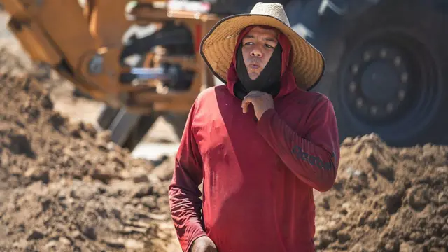 Trabalhador da construção civil em Irvine, na Califórnia, puxa para baixo sua máscara facial durante uma onda de calor em 2024