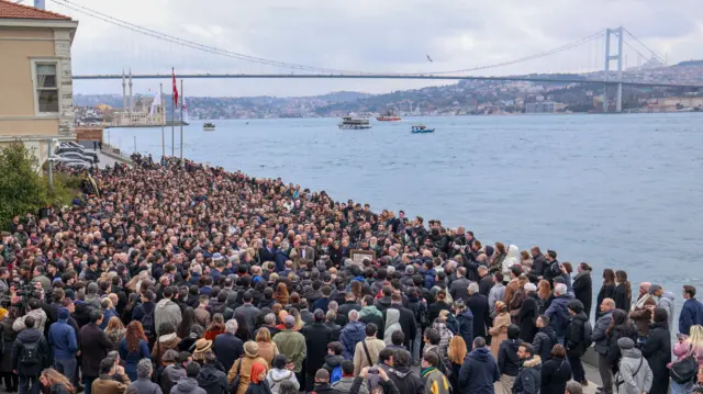 Kalabalık bir grup Galatasaray Üniversitesi'nin bahçesinde toplanmış. Yukarıdan çekilmiş fotoğrafta arkada İstanbul Boğazı görünüyor. 