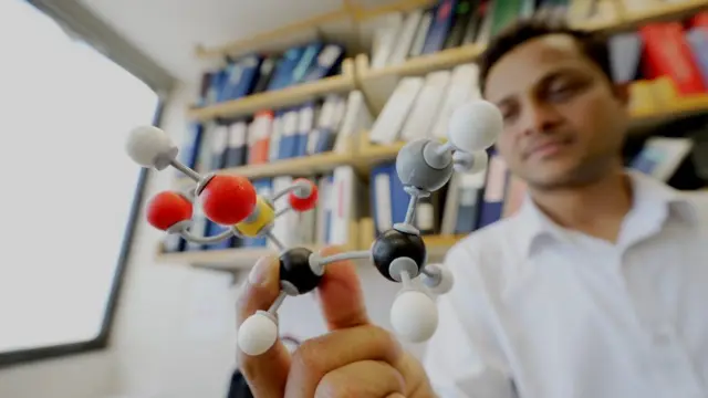 Dr Yadav elinde torinin kimyasal modelini tutuyor