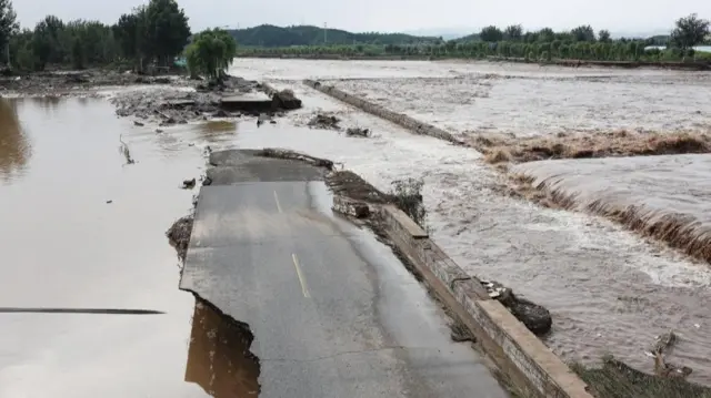 道路が洪水の影響で破壊、寸断されている。周囲では濁った水が大量に流れている