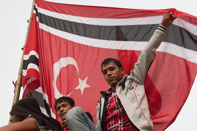 Para pengunjuk rasa asal Aceh mengibarkan bendera separatis yang dilarang dalam sebuah aksi protes di luar wisma tamu gubernur di Banda Aceh pada 4 April 2013, saat Menteri Dalam Negeri Indonesia Gamawan Fauzi bertemu dengan Gubernur Aceh Zaini Abdullah. Ribuan pengunjuk rasa berkumpul di Aceh, Indonesia, untuk mendukung upaya para pemimpin daerah menjadikan bendera separatis tersebut sebagai lambang resmi provinsi yang sangat menjunjung nilai-nilai Islam itu. AFP PHOTO / CHAIDEER MAHYUDDIN (Kredit foto harus mencantumkan